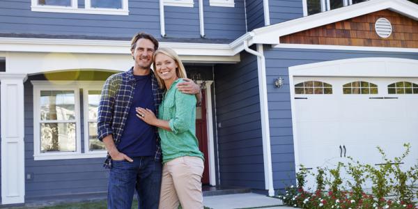man and woman standing in front of a blue house