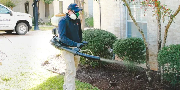 Technician spraying for mosquitoes, exterior of home